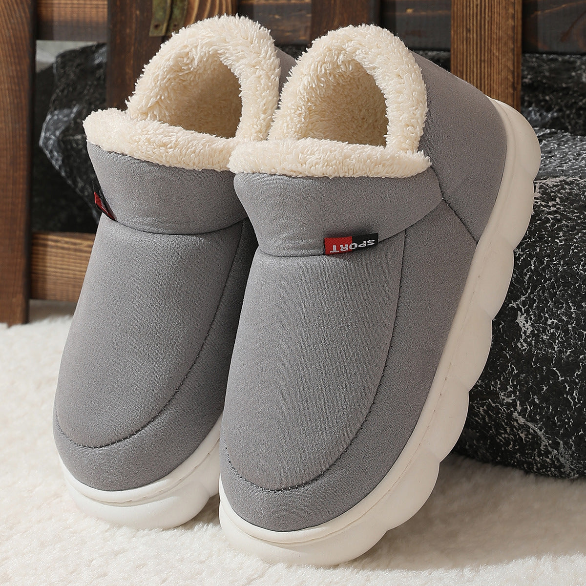 Grey plush house shoes with fuzzy strap and thick white sole, angled view