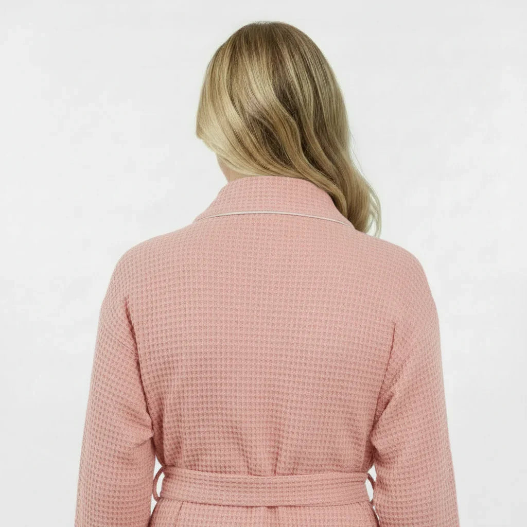 Women’s waffle bathrobe in blush pink with light piping and tie belt, rear view.