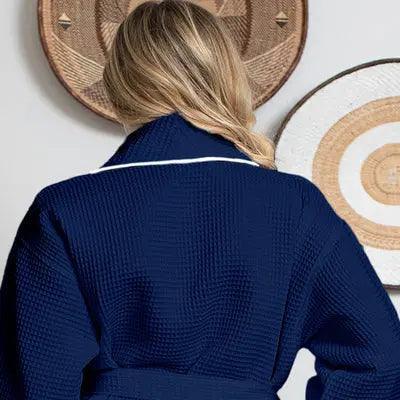 Women’s waffle bathrobe in navy with white piping and tie belt, rear view.