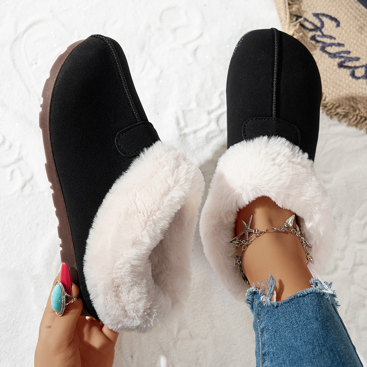 Women's snow boots in black with white faux-fur lining and side hook strap