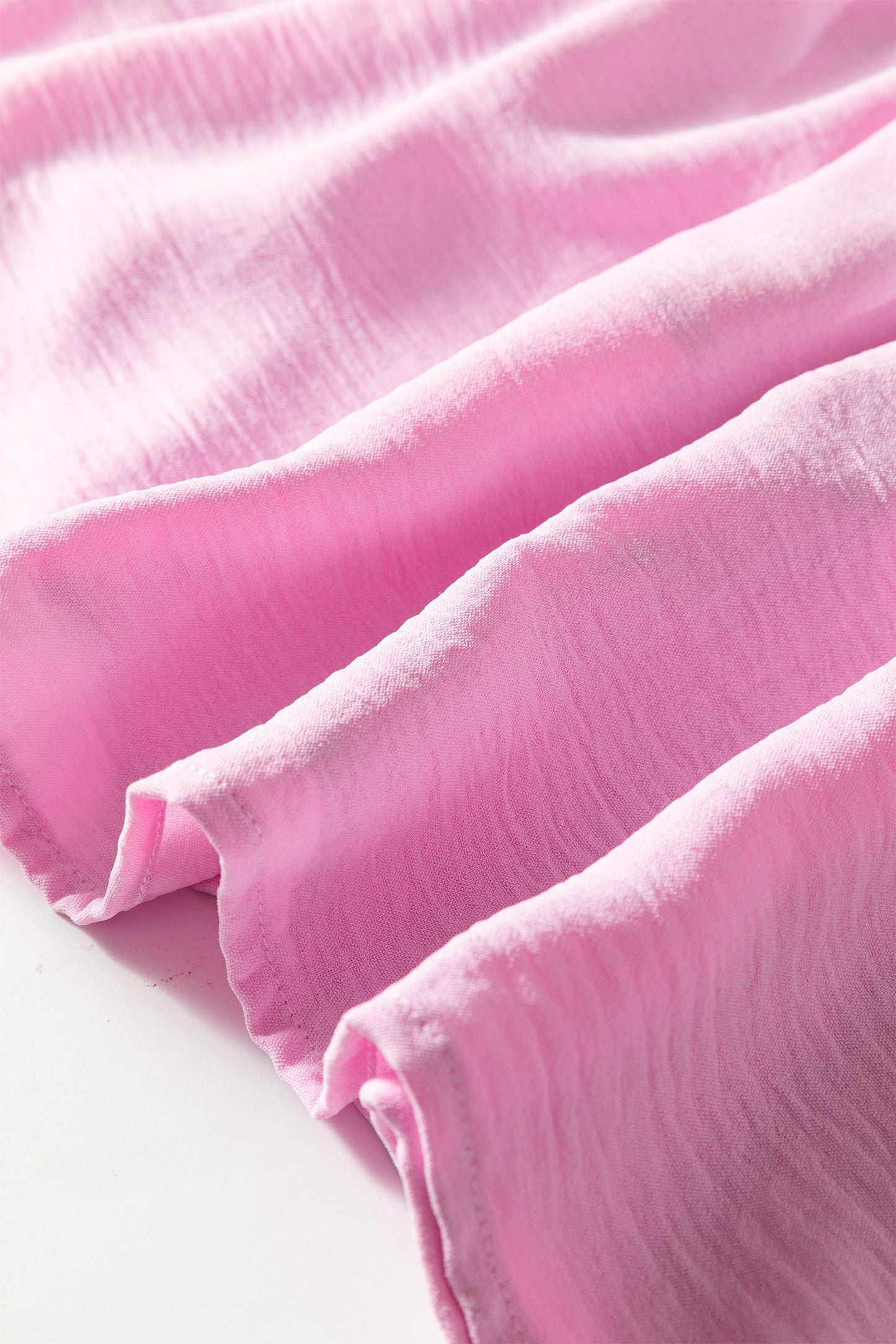Pink tiered midi dress fabric close-up with layered ruffle hem