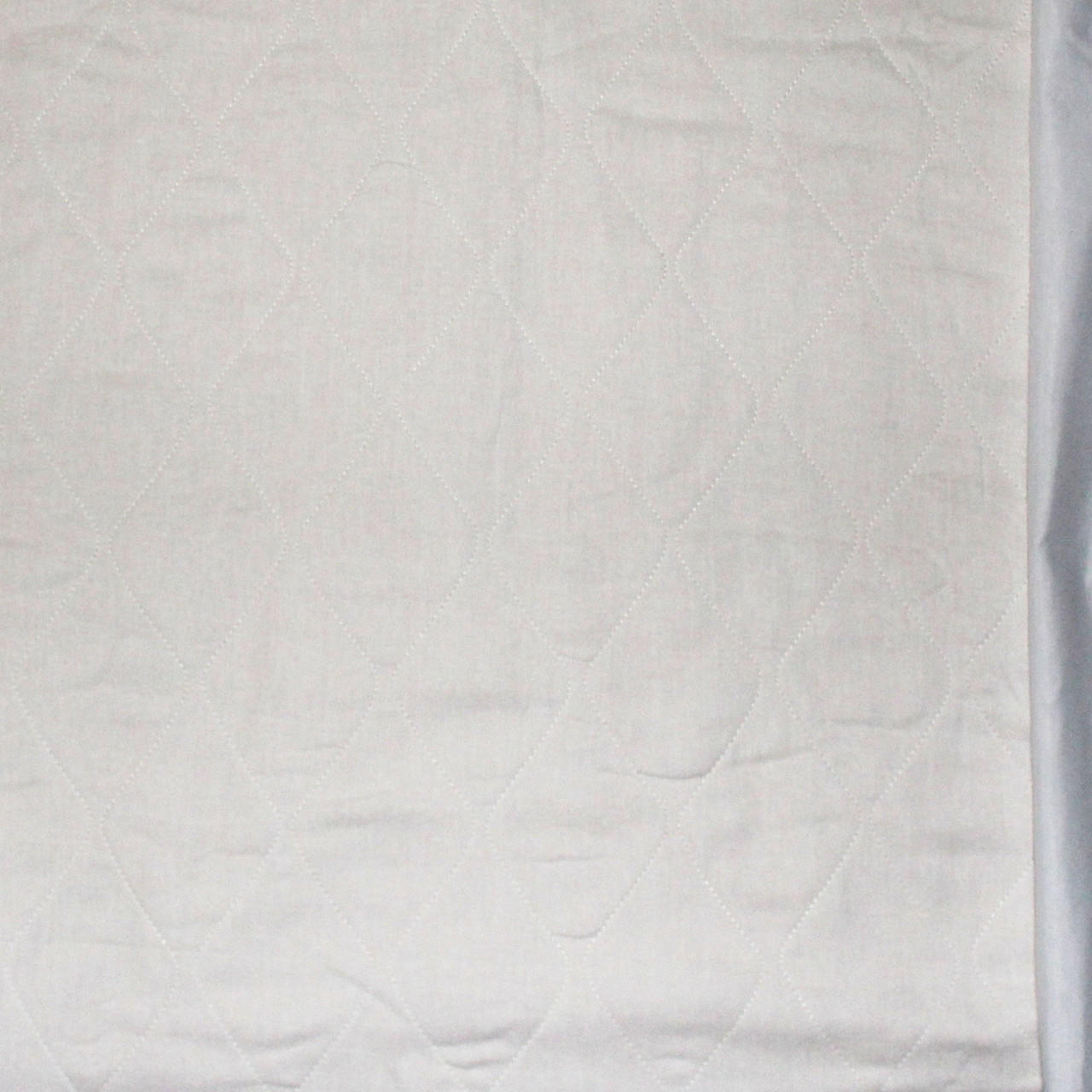 Close-up of white birdseye quilted underpad fabric surface