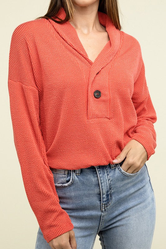 Tomato textured pullover top with V-neck, button closure, chest pocket, ribbed cuffs