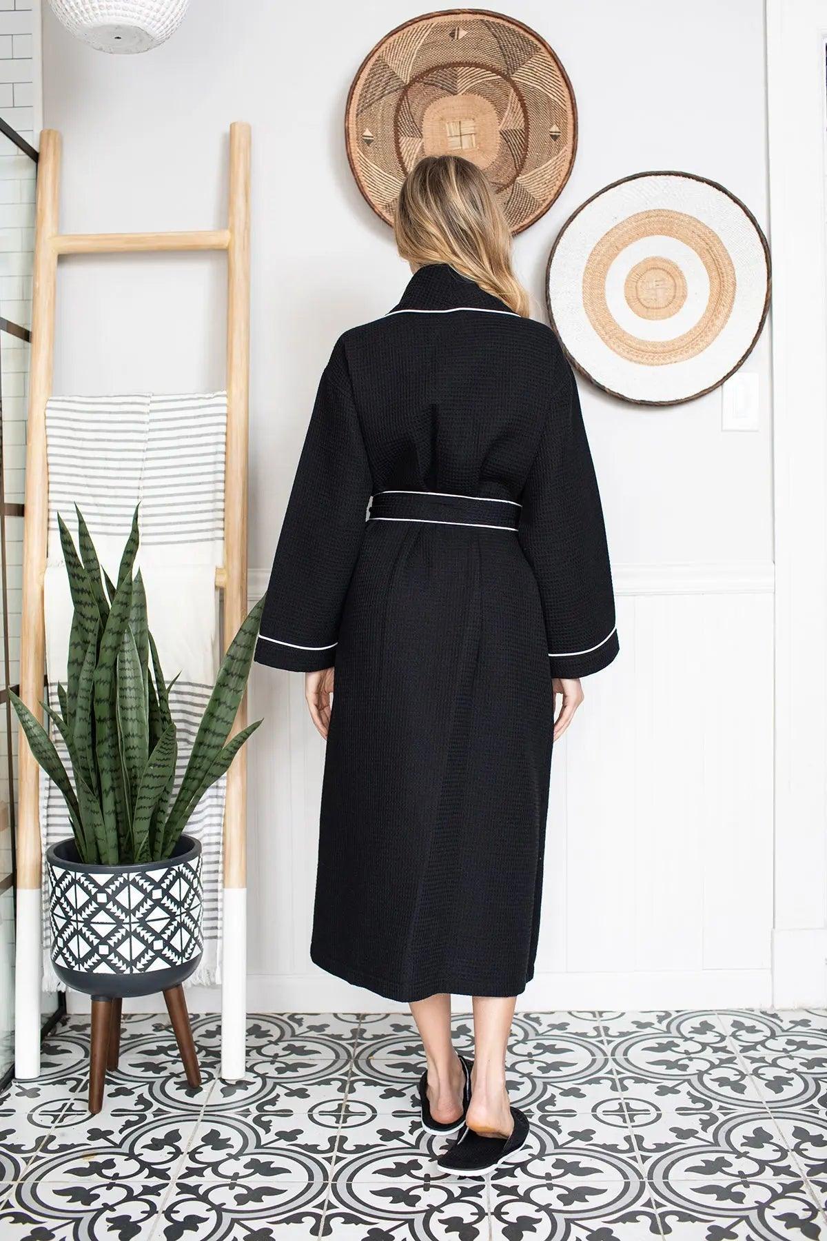 Women’s waffle bathrobe in black with white piping, back view with tie belt
