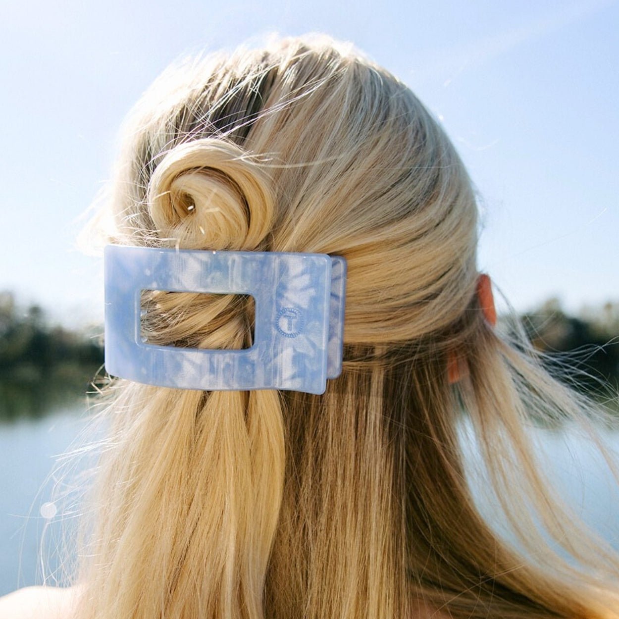 Medium light blue rectangle hair clip holding blonde hair in a side twist