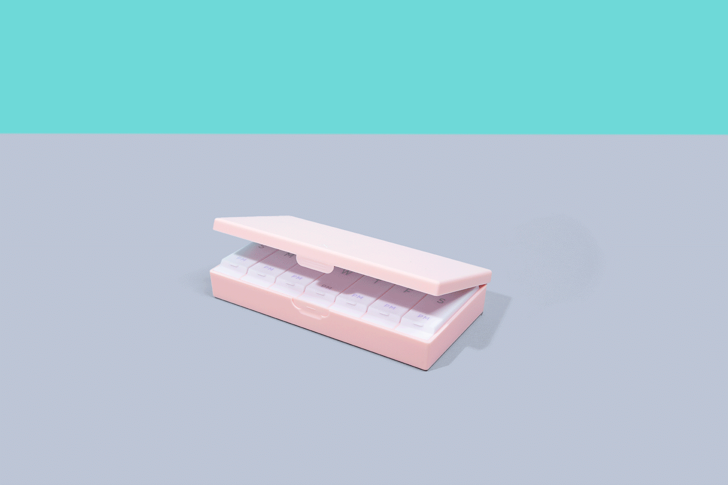 Blush pink AM/PM pill box with sliding tray of labeled compartments