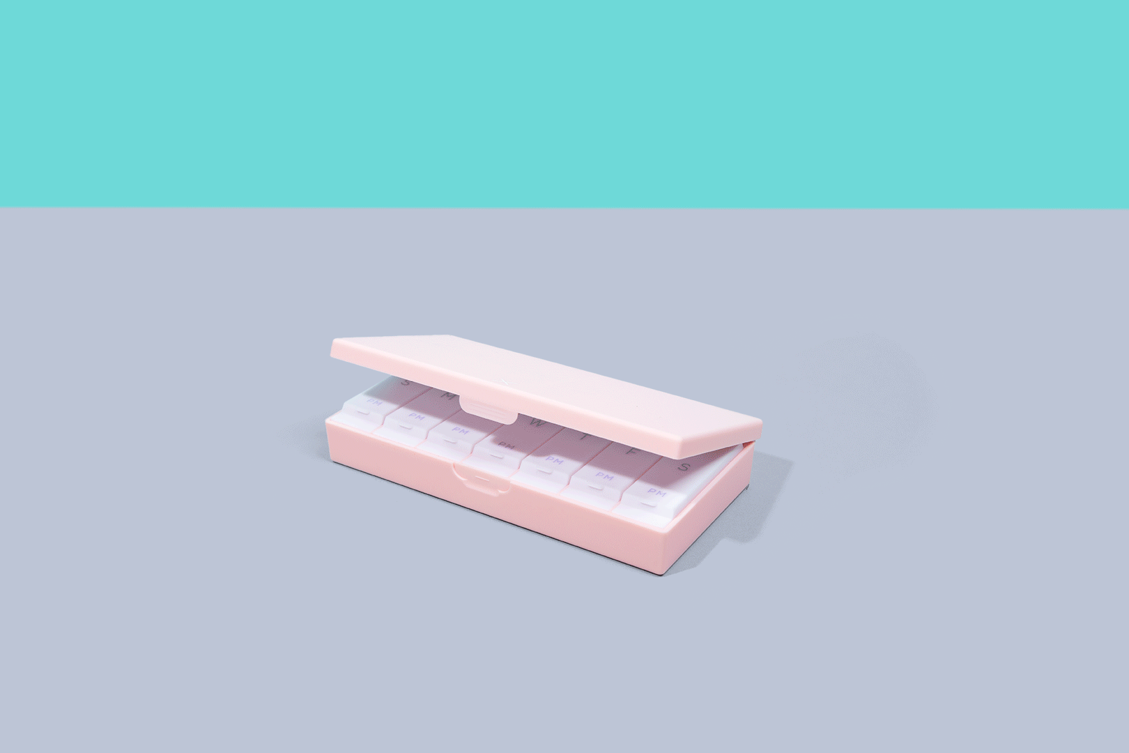 Blush pink AM/PM pill box with sliding tray of labeled compartments