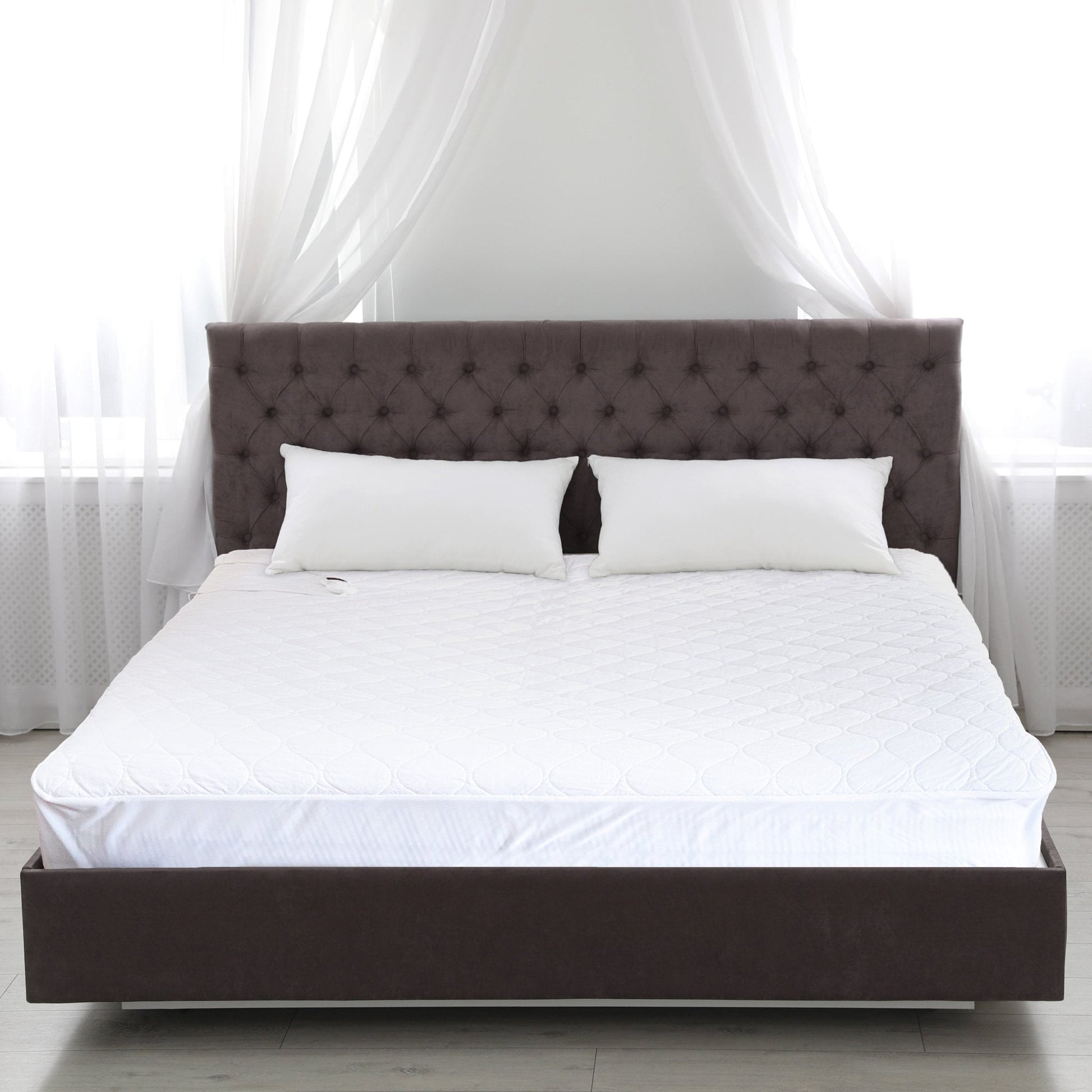 White heated mattress pad with quilted top on a bed, showing seam and edges