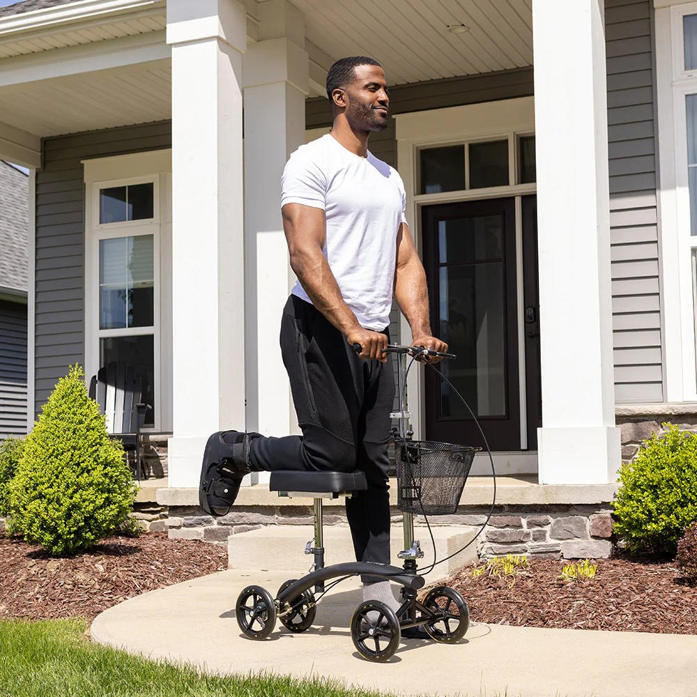 Knee walker with padded knee support, front basket, and four rolling wheels outdoors