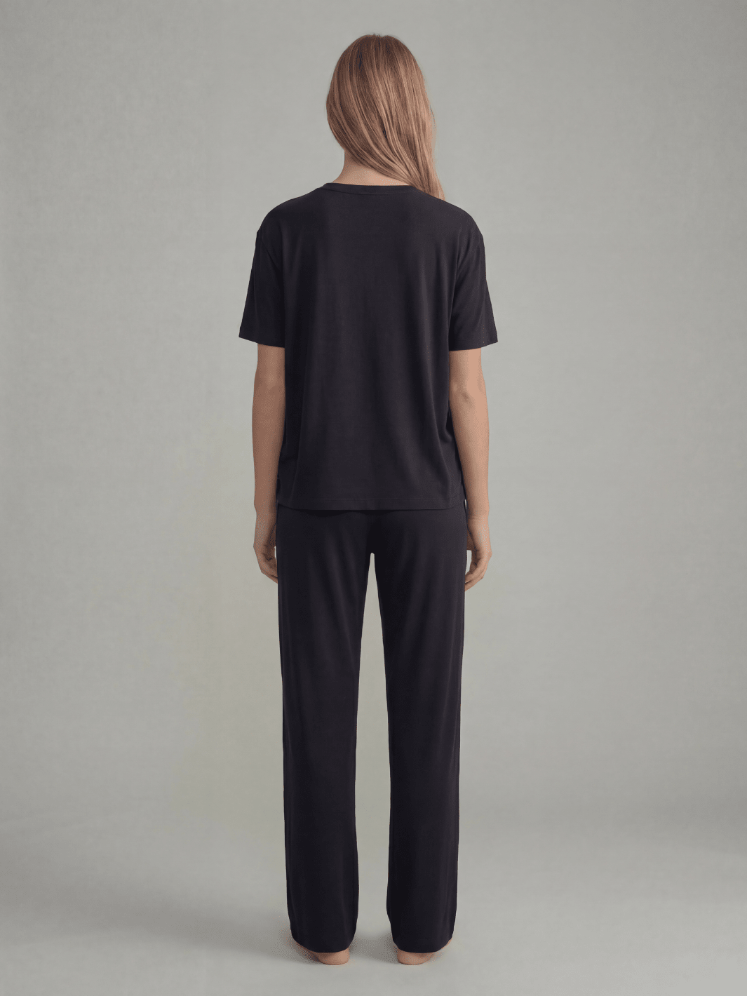 Black pajama pants, back view, elastic waist and wide-leg straight legs.