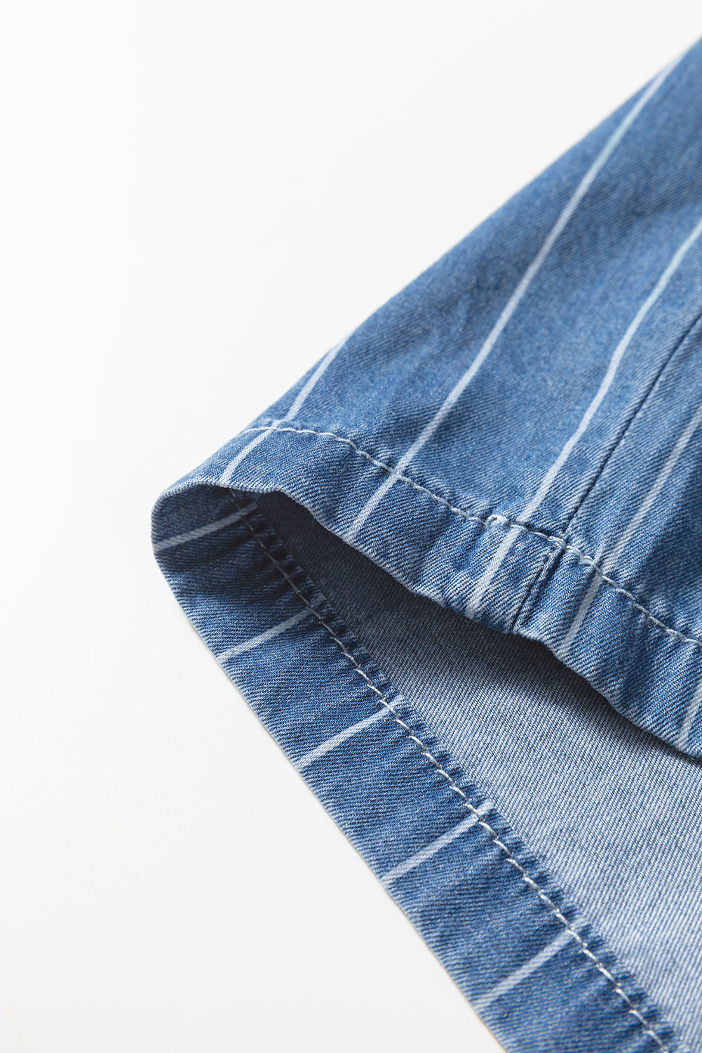 Blue pinstripe denim trouser hem with visible stitching and curved edge