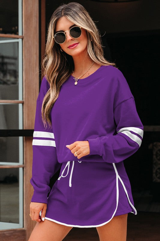 Purple pullover and mini skirt set, long sleeves with white striped accents and drawstring waist.