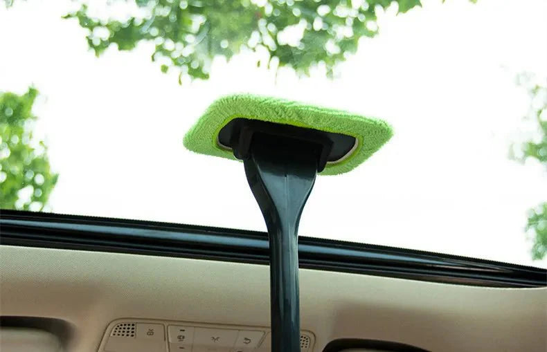 Green microfiber car window cleaning brush head on a black pole above windshield