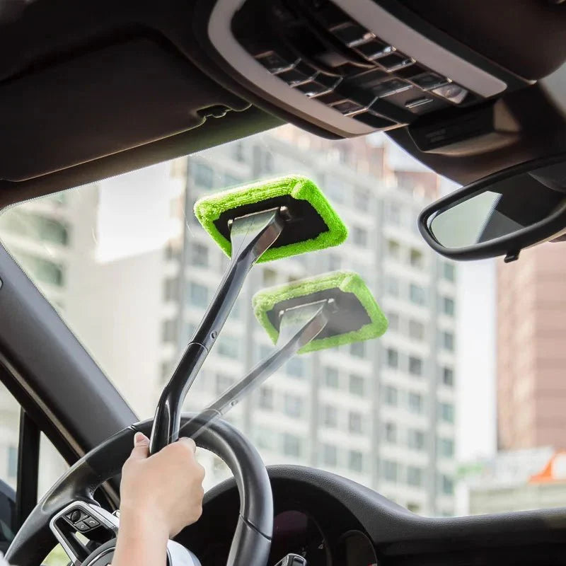Green microfiber car window brush on a black pole, held near the dashboard