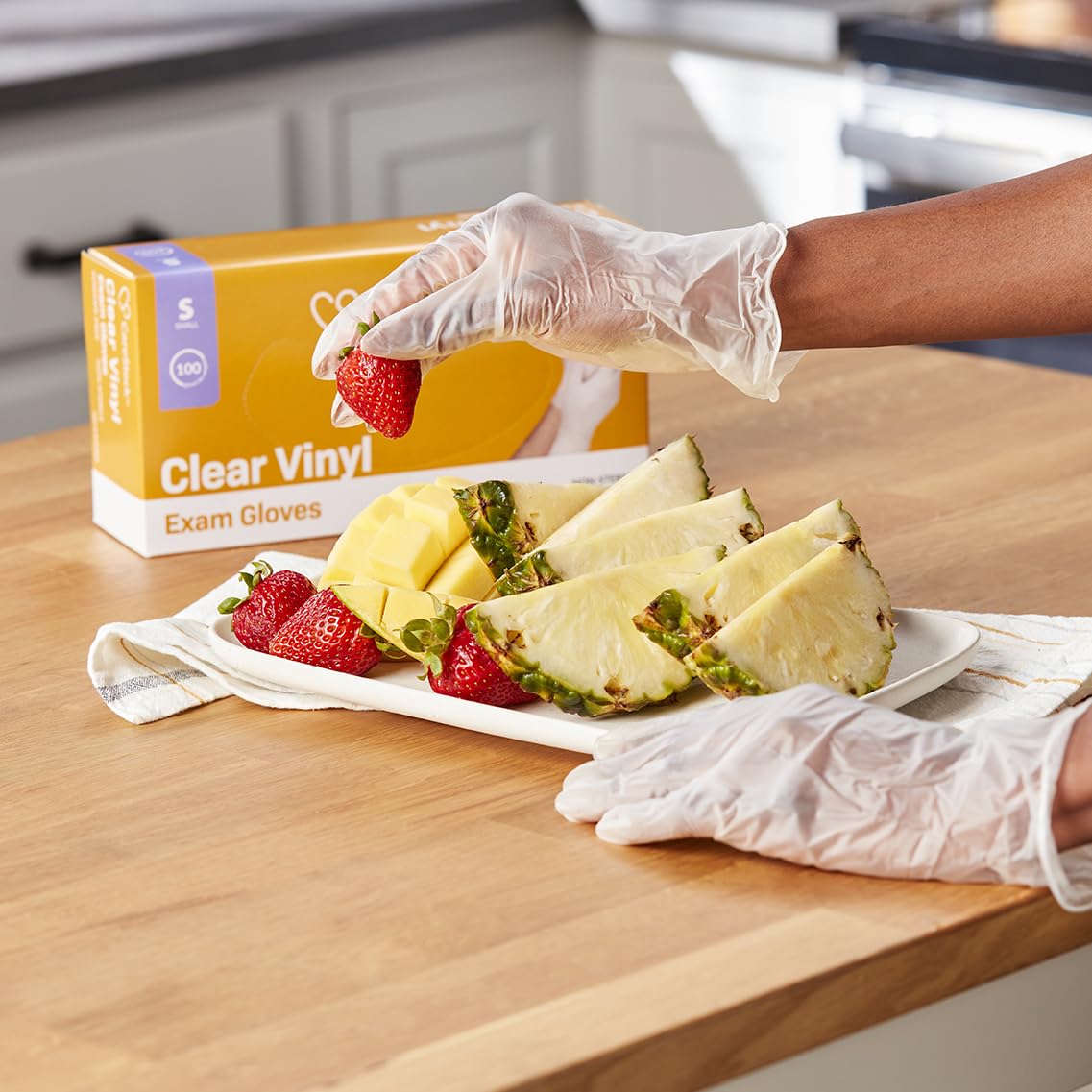 Clear vinyl exam gloves on hands, standard cuff, powder-free, in-use view