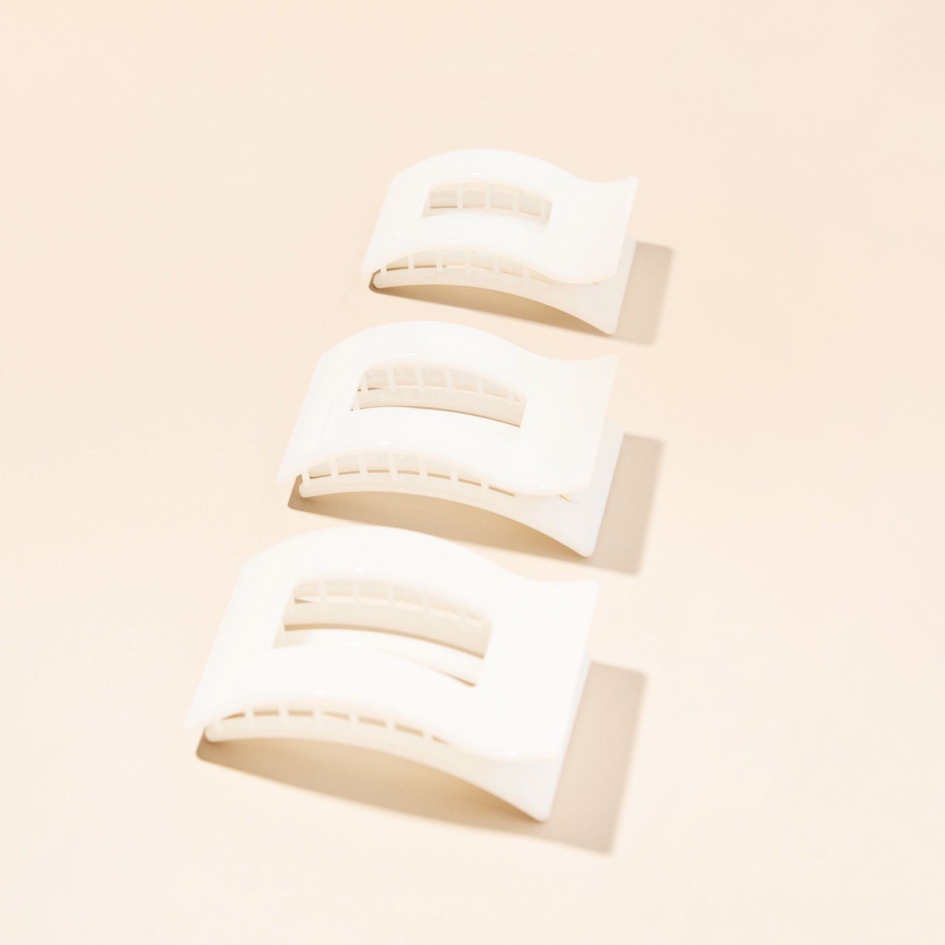 Multiple small white rectangle hair clips, shown from different angles