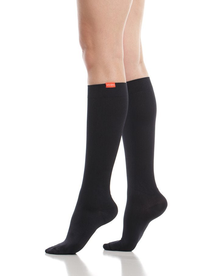 Black cotton compression socks on legs, smooth knit leg with cuff logo