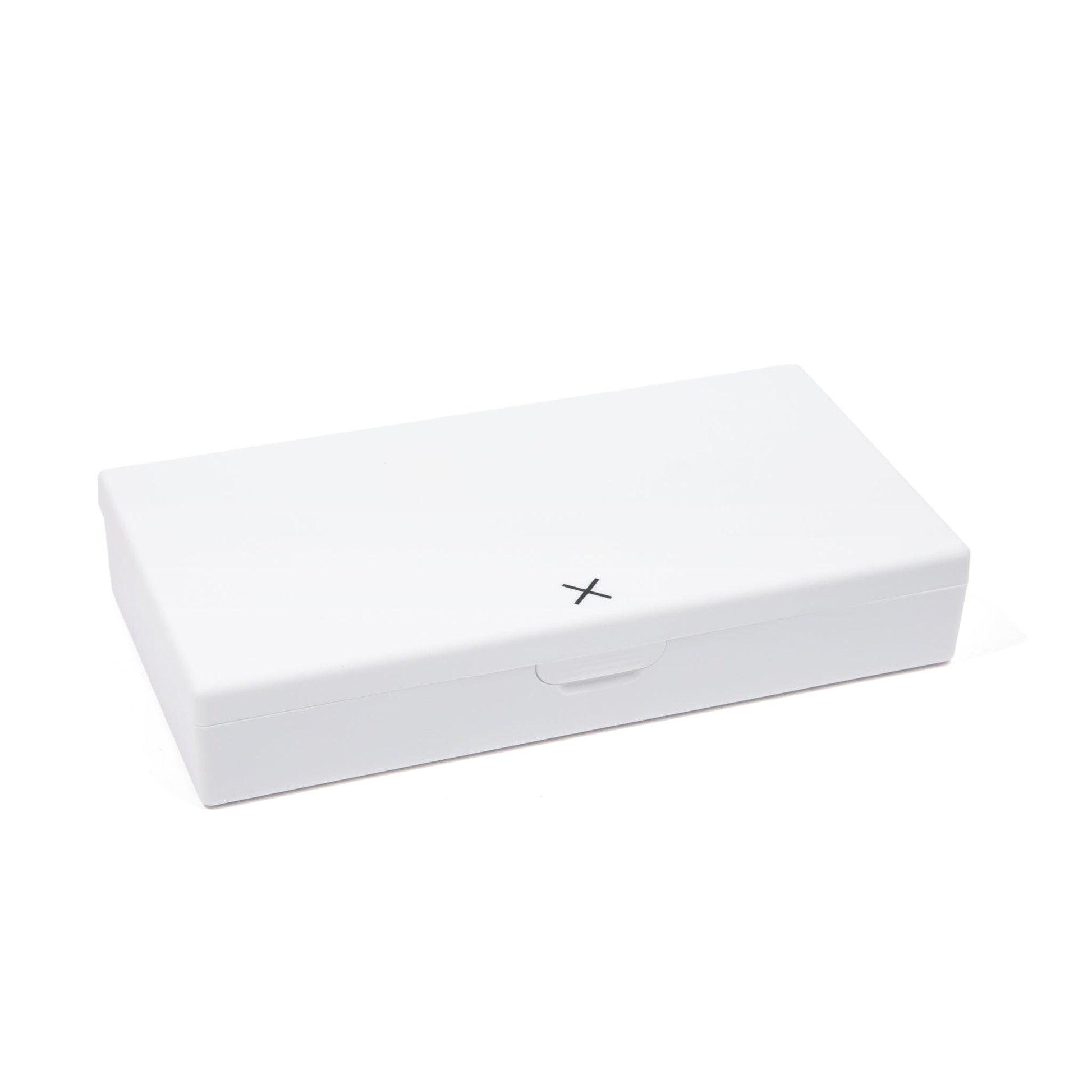 White pill box with hinged lid and X marking on the front