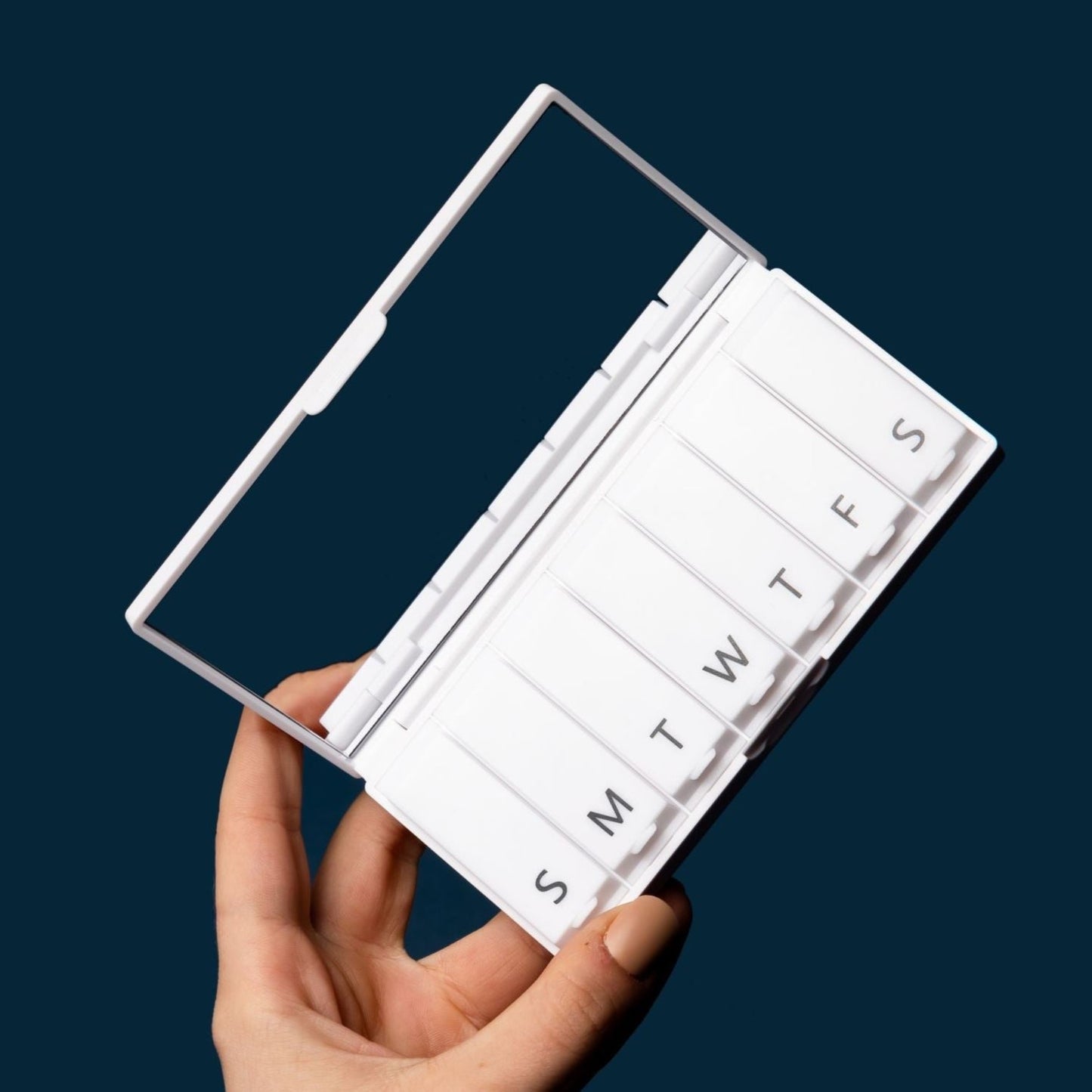 White pill box open, showing day labels S T W F and S compartments