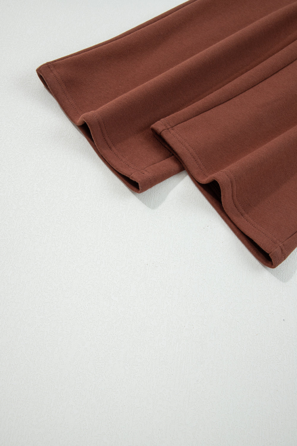 Coffee-brown pant cuffs and hem stitching detail on solid pants