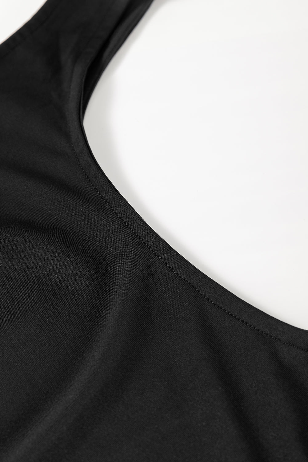 Black sleeveless dress armhole seam and curved neckline close-up