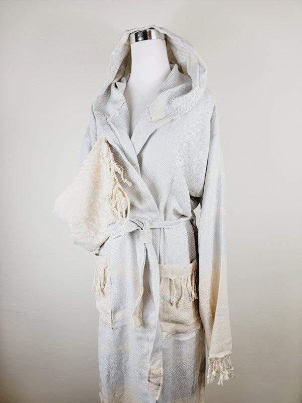 Off-white hooded robe with tie belt and patch pockets, tassel-trim cuffs