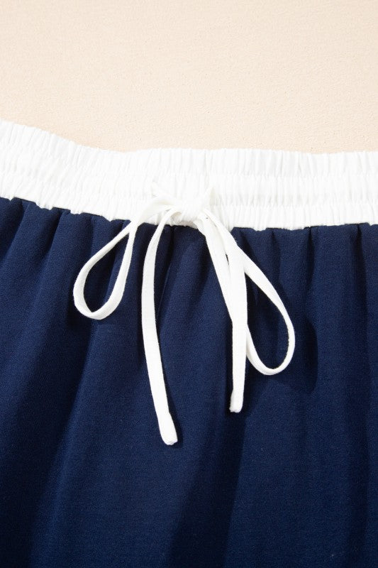 Navy mini skirt detail: white smocked waistband and drawstring bow ties.