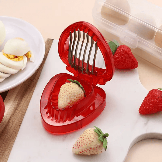 Red strawberry slicer with sliced strawberries on a table