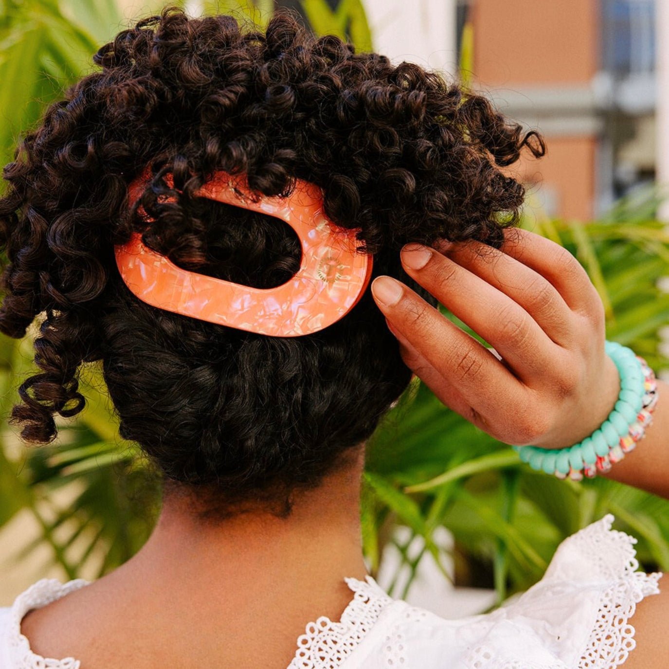 Translucent pink hair clip securing curly hair