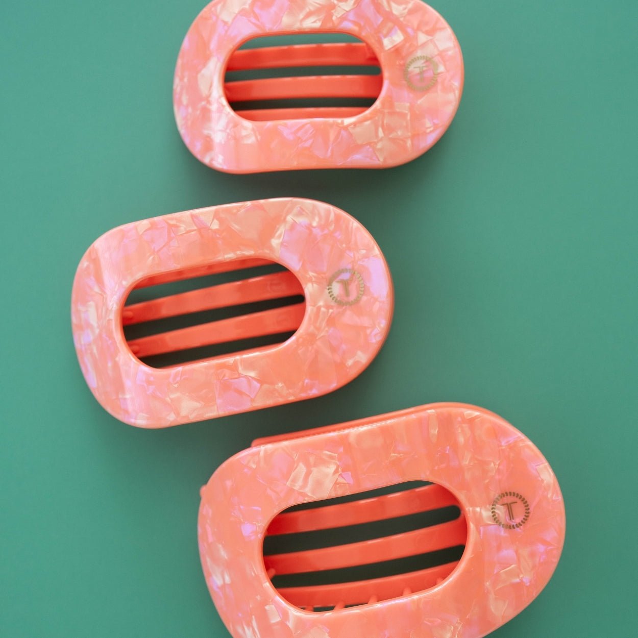 Three translucent pink flat round hair clips with three-bar centers, faux-marble pattern