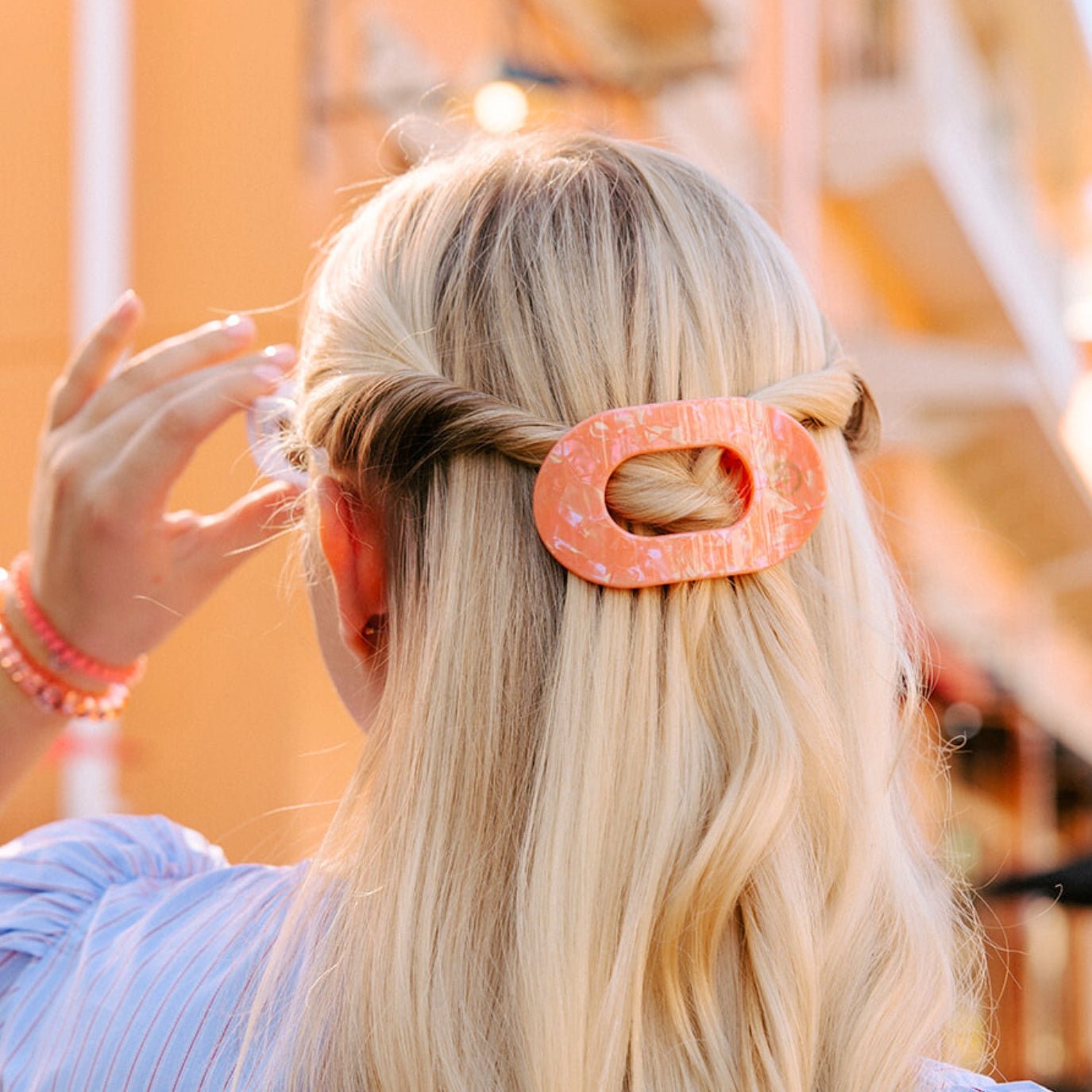 Pink oval hair clip securing blonde hair with twisted section