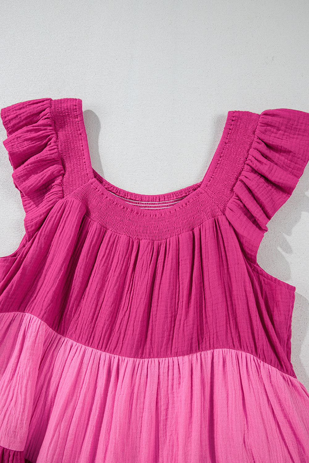Close-up of pink tiered mini dress bodice with ruffled flutter sleeve detail