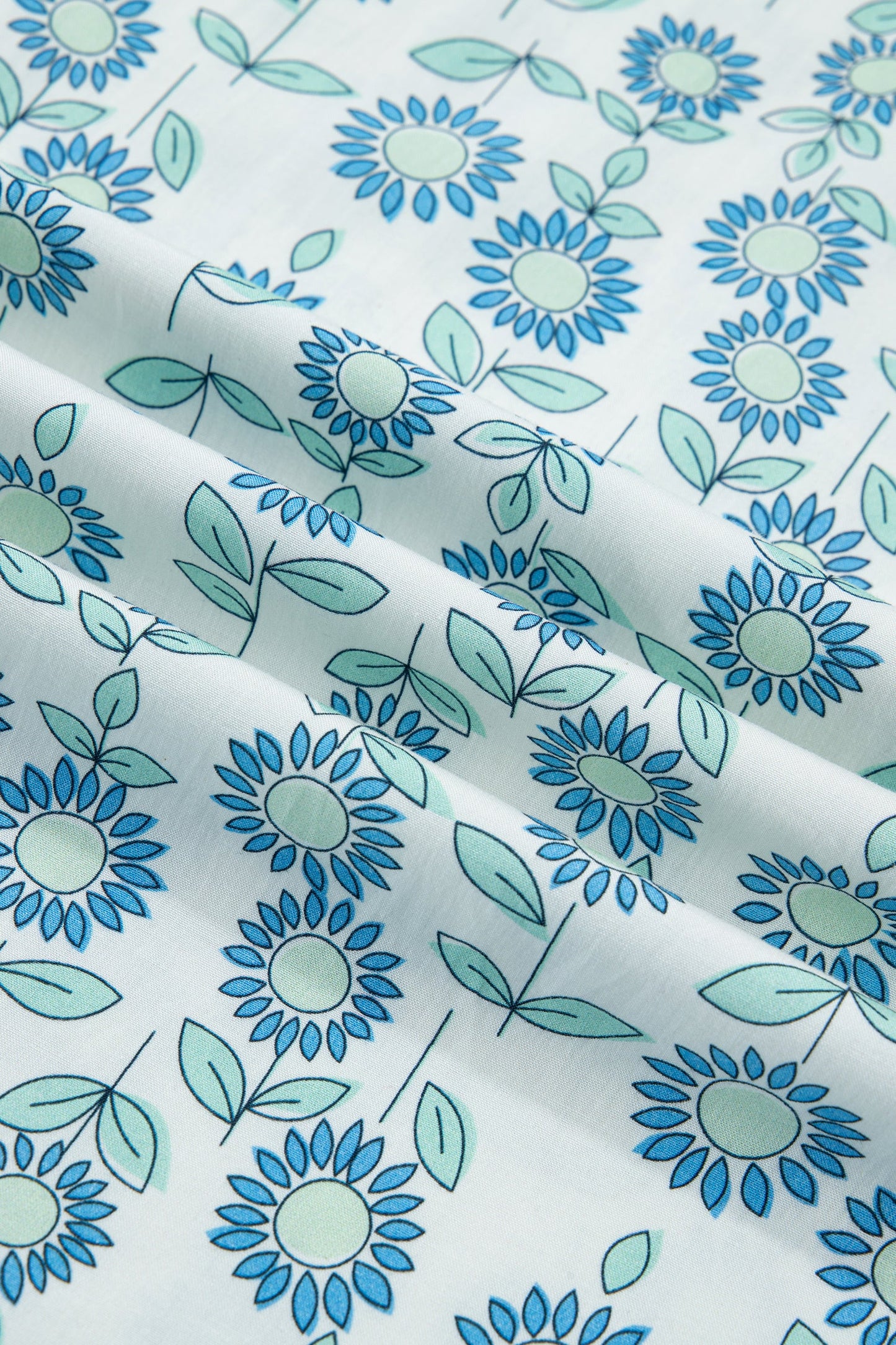 Close-up of sky blue fabric with teal and blue daisy-like floral print