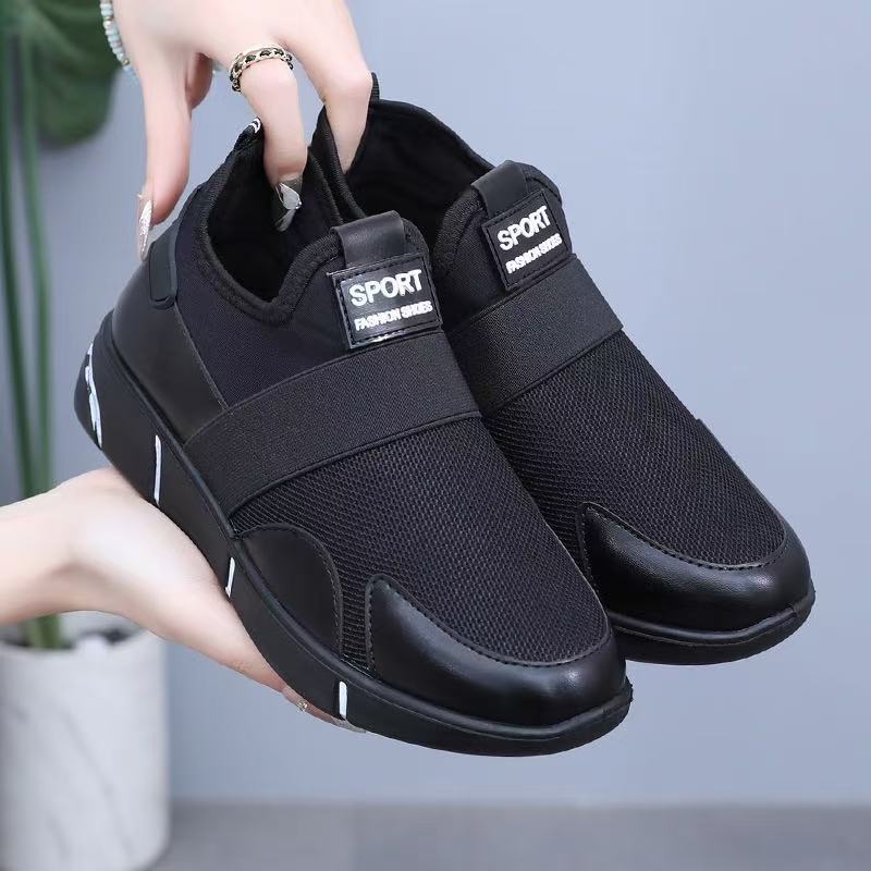 Black slip-on walking shoe with wide strap, sport patch, and textured rubber outsole