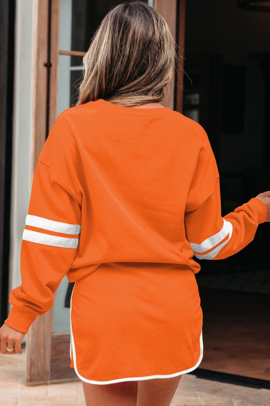 Orange pullover and mini skirt set, back view with white striped cuffs and curved hem.