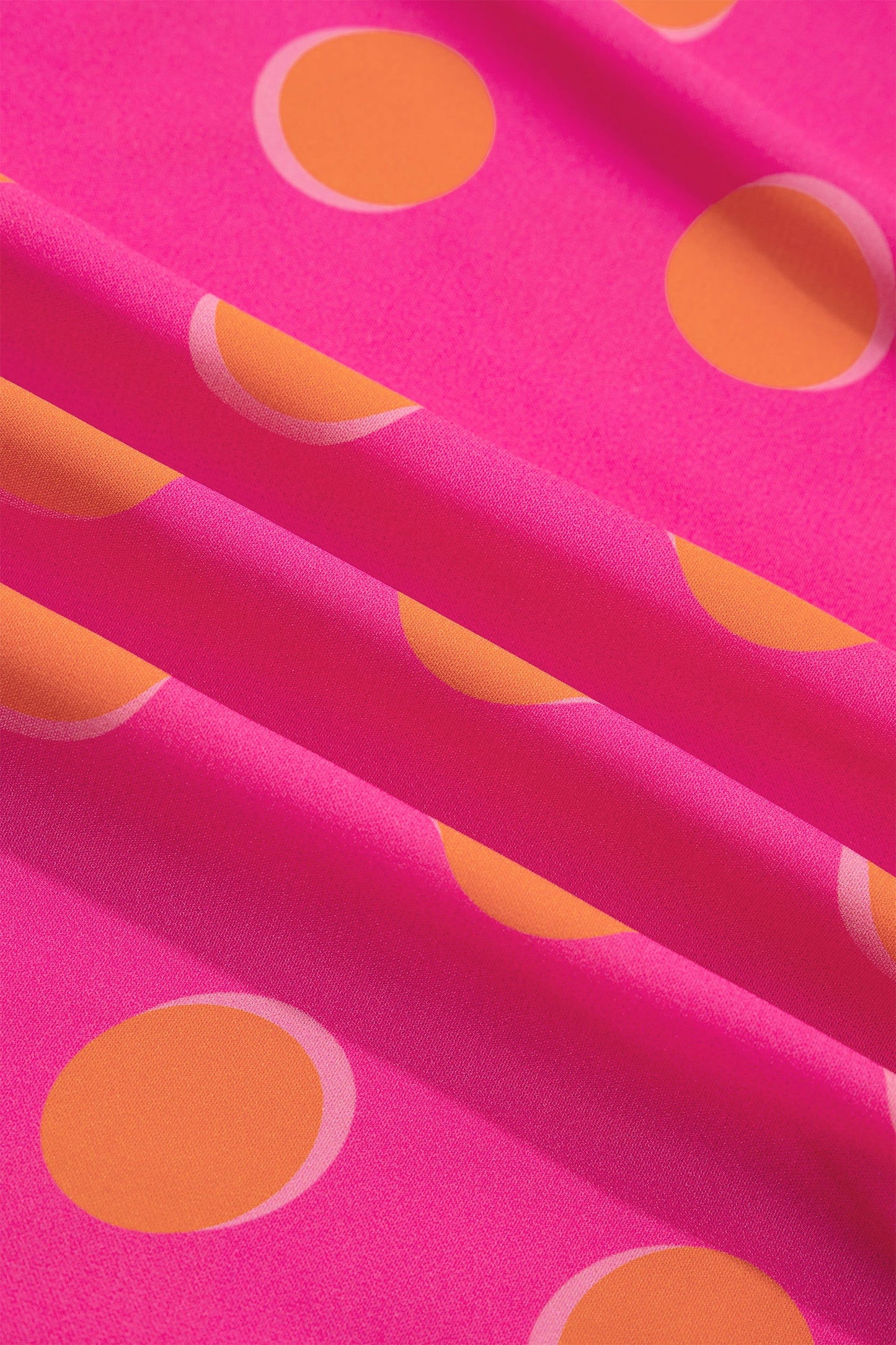 Rose fabric close-up with orange oval polka dots on a smooth knit