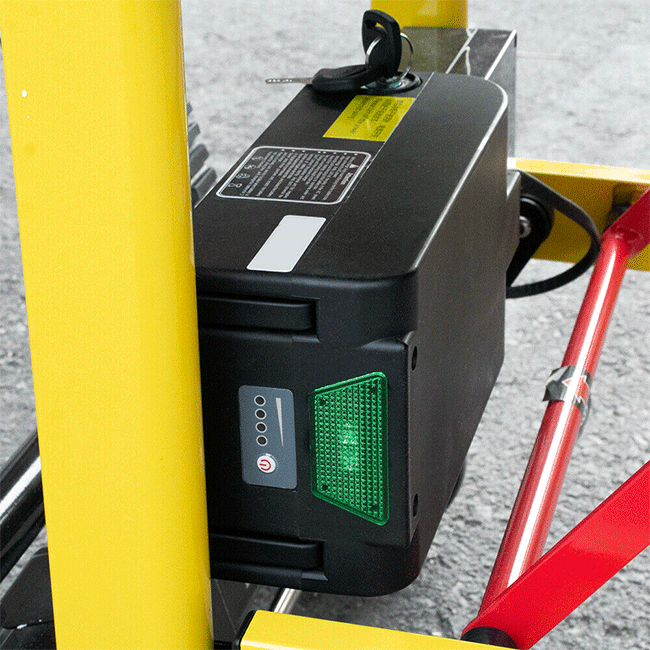 Black battery pack with green status light on yellow stair-climbing wheelchair lift