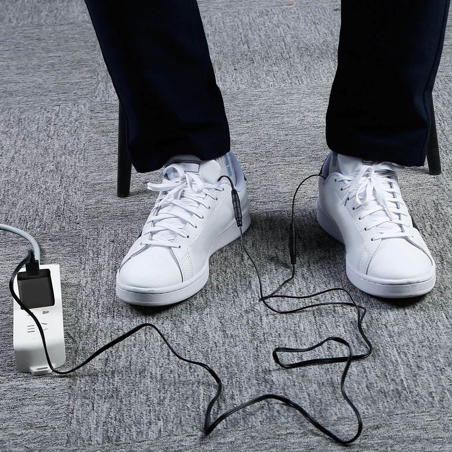 USB heated insoles under white sneakers with controller unit and trailing cords