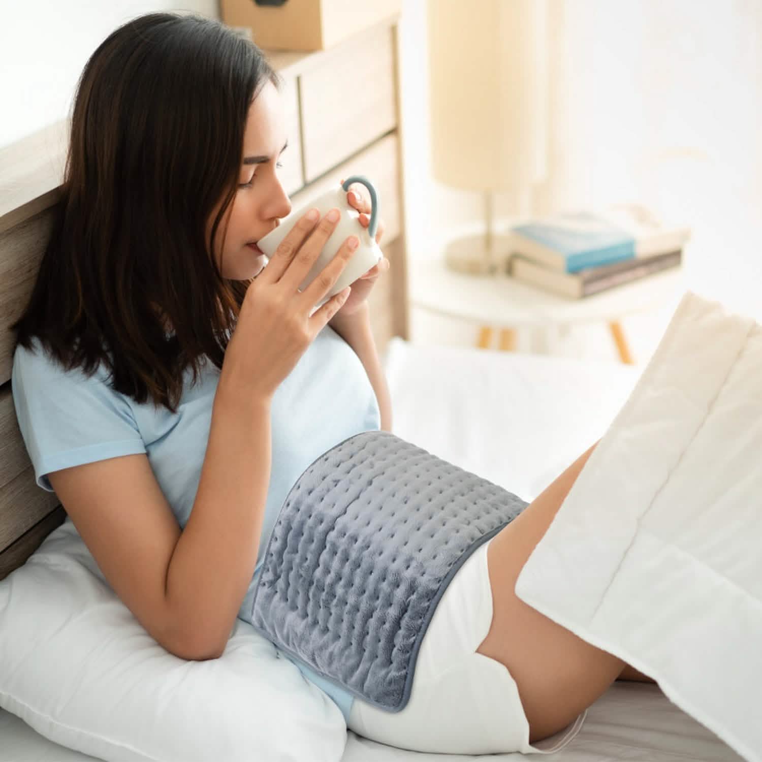 Grey heating pad with dotted quilt pattern, draped on couch beside legs