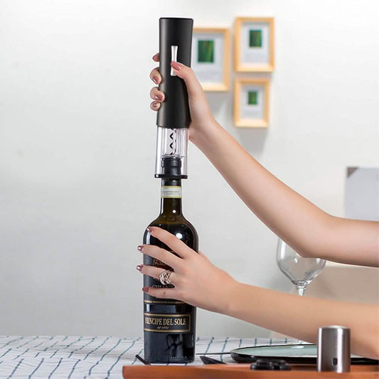 Black electric wine bottle opener held above a wine bottle with hands and corkscrew