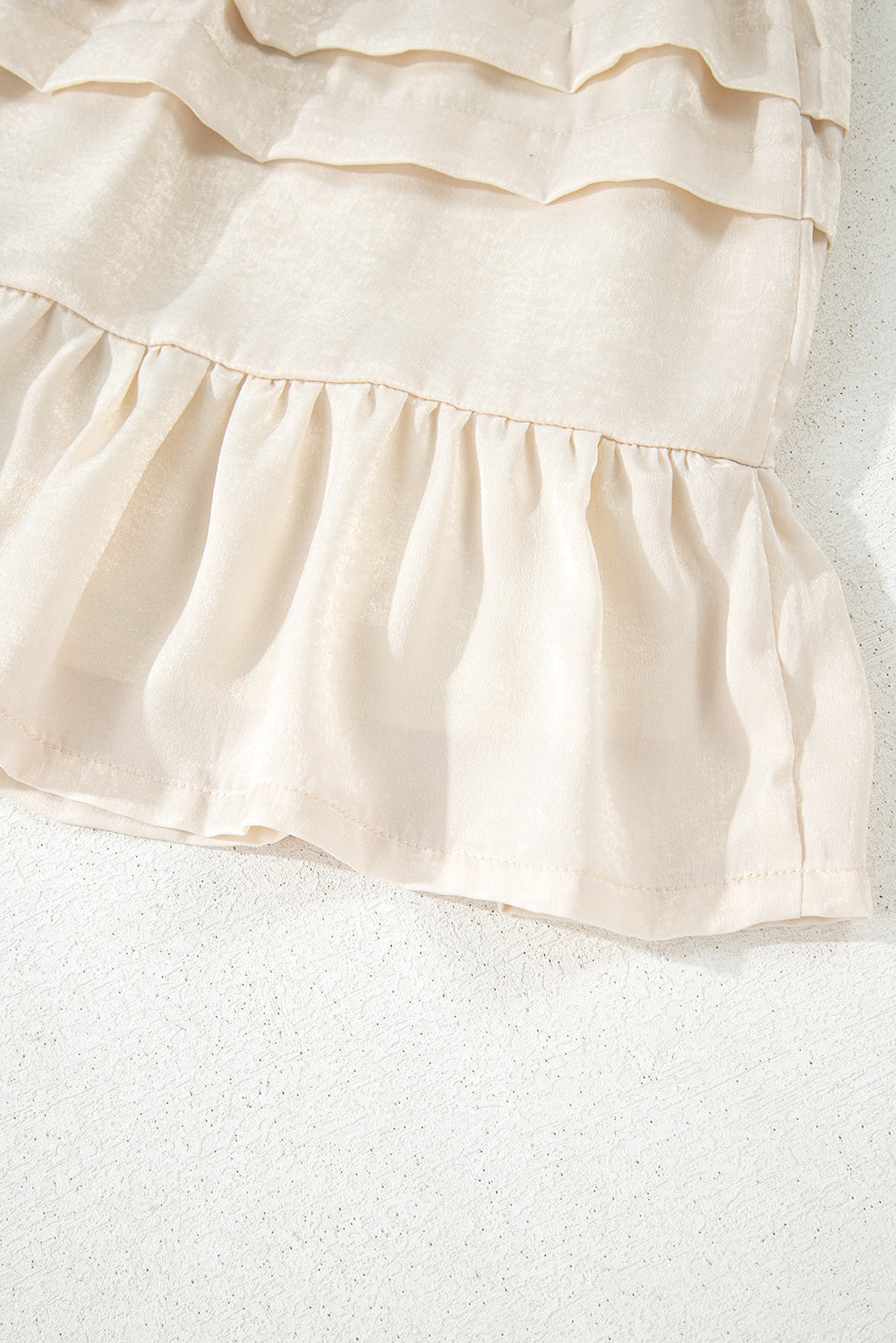 Beige tiered mini skirt hem with gathered ruffle layers and soft pleats