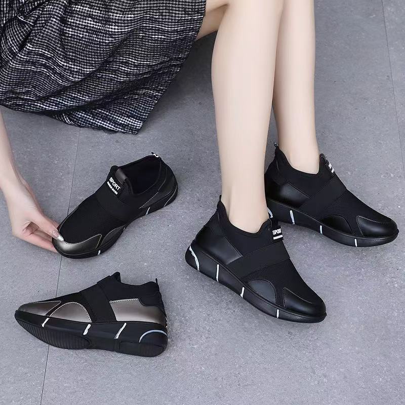 Black slip-on sneakers on feet with sport patch and contrasting white piping