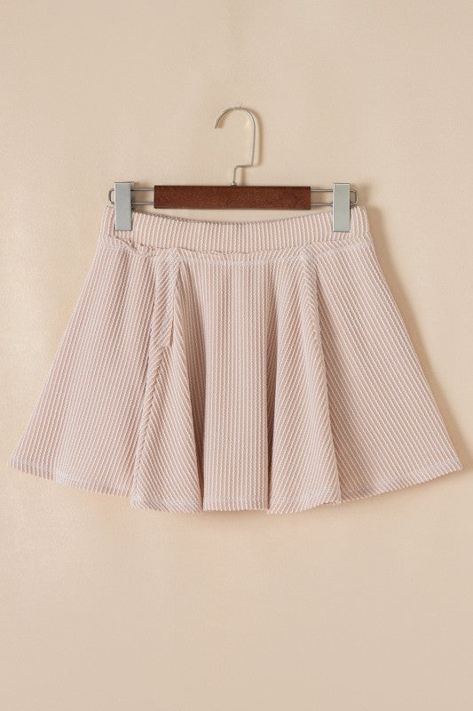Pink ruffle mini skirt on hanger with gathered waistband and pleated skirt panels