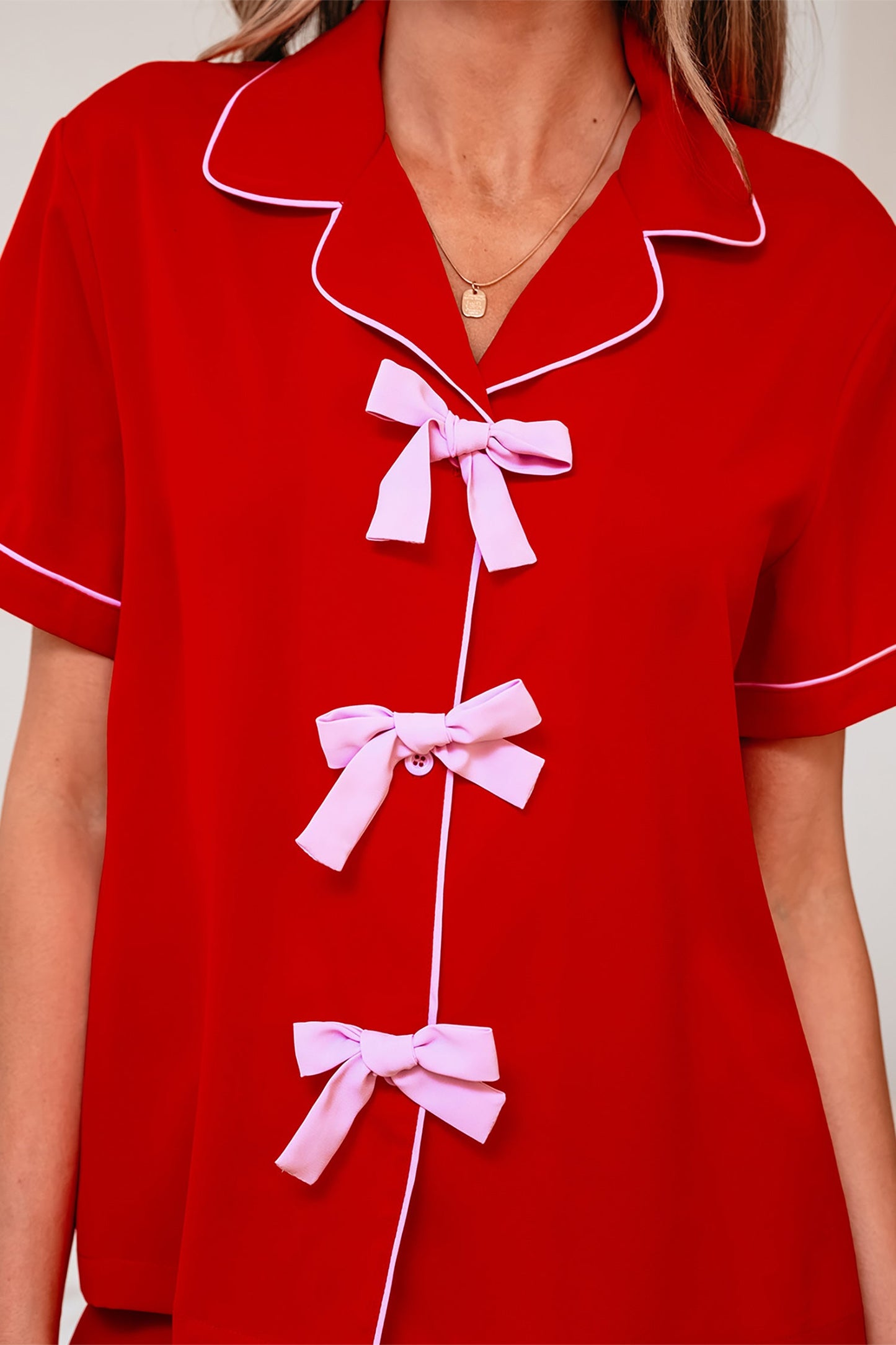 Red pajama top close-up with bow-tie placket and contrast white piping along collar