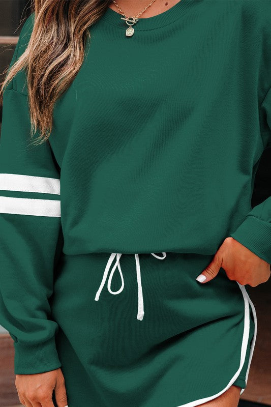 Green crew pullover with white striped cuff; green mini skirt with drawstring ties