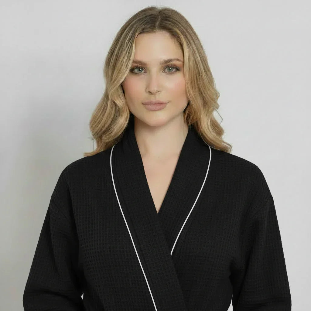 Women’s knee-length waffle robe in black with white piping, V-neck and belt tie
