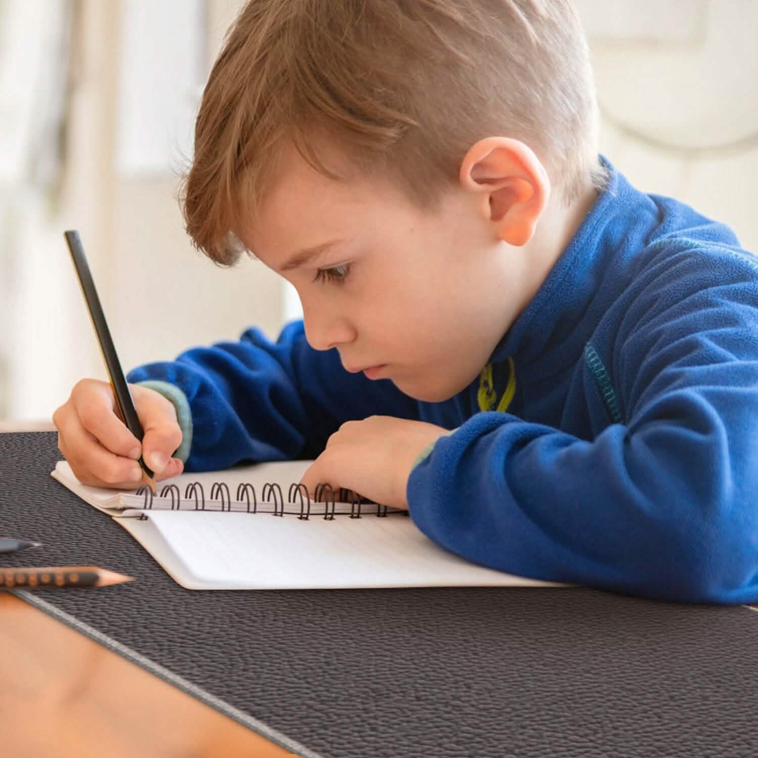 Heated gaming mouse pad, dark gray surface used for writing by a child