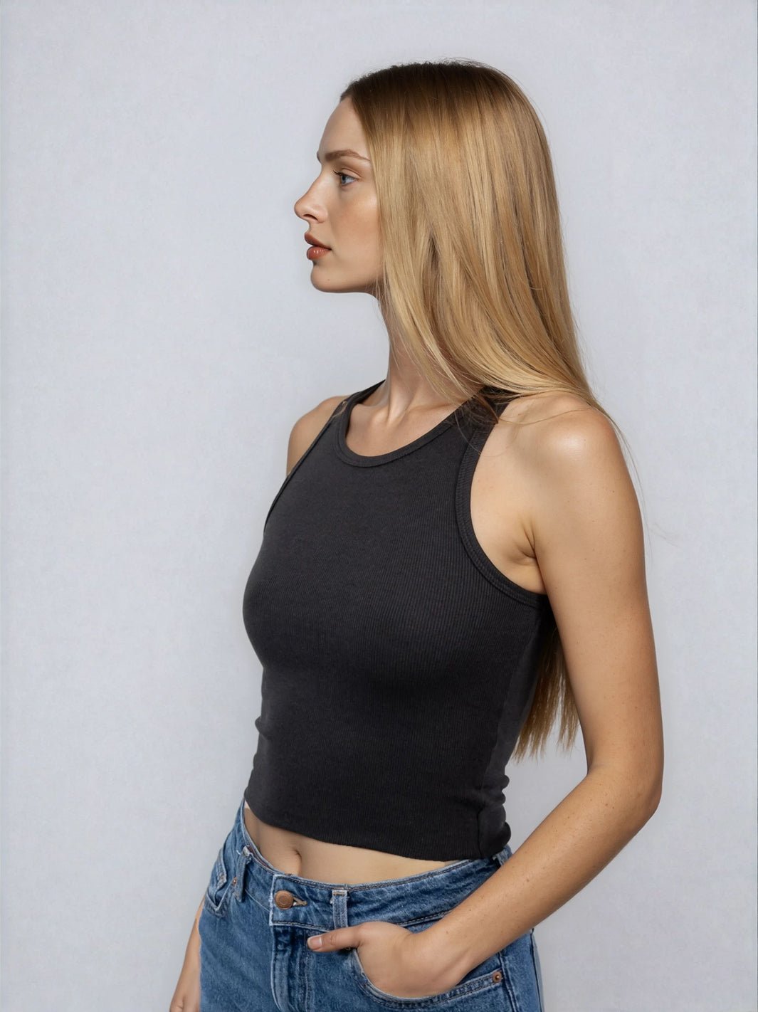 Black high-neck sleeveless cropped tank with raw hem, side profile view.