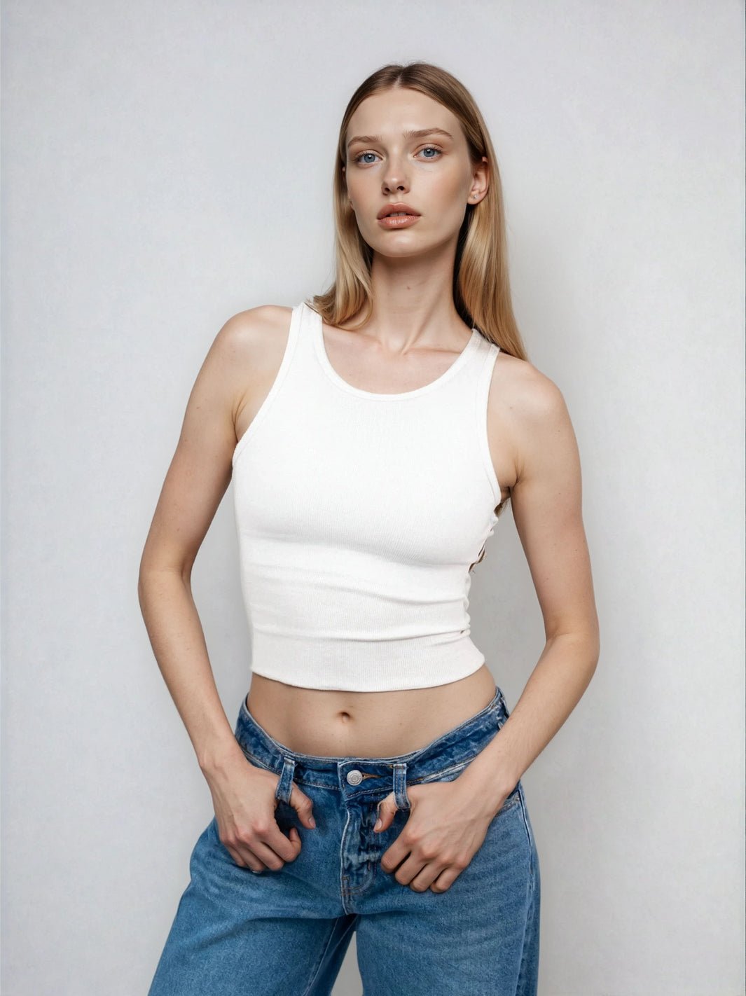 White high-neck sleeveless cropped tank with raw hem edge, close-up front view.