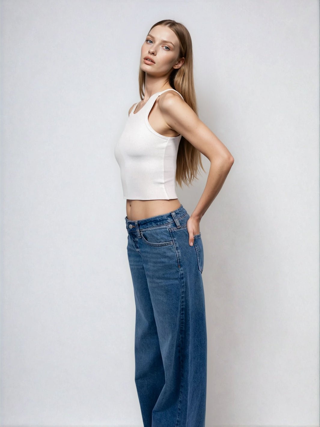 White high-neck sleeveless cropped tank with raw hem, shown from a side angle.